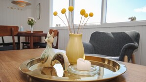 Ein Esstisch mit einer Keramik-Fuchs-Figur, einer gelben Vase mit gelben Blumen und einem weißen Kerzen.