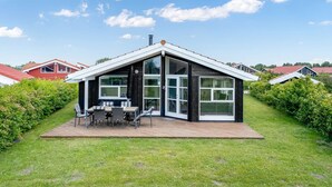 A modern house with a large glass door, a deck with outdoor furniture, and a red roof. - "Birtir" - 1.2km from the sea by Interhome (Væggerløse)