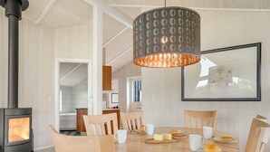 A dining area with a round wooden table, six chairs, a hanging light fixture, and a wood-burning stove. - "Birtir" - 1.2km from the sea by Interhome (Væggerløse)