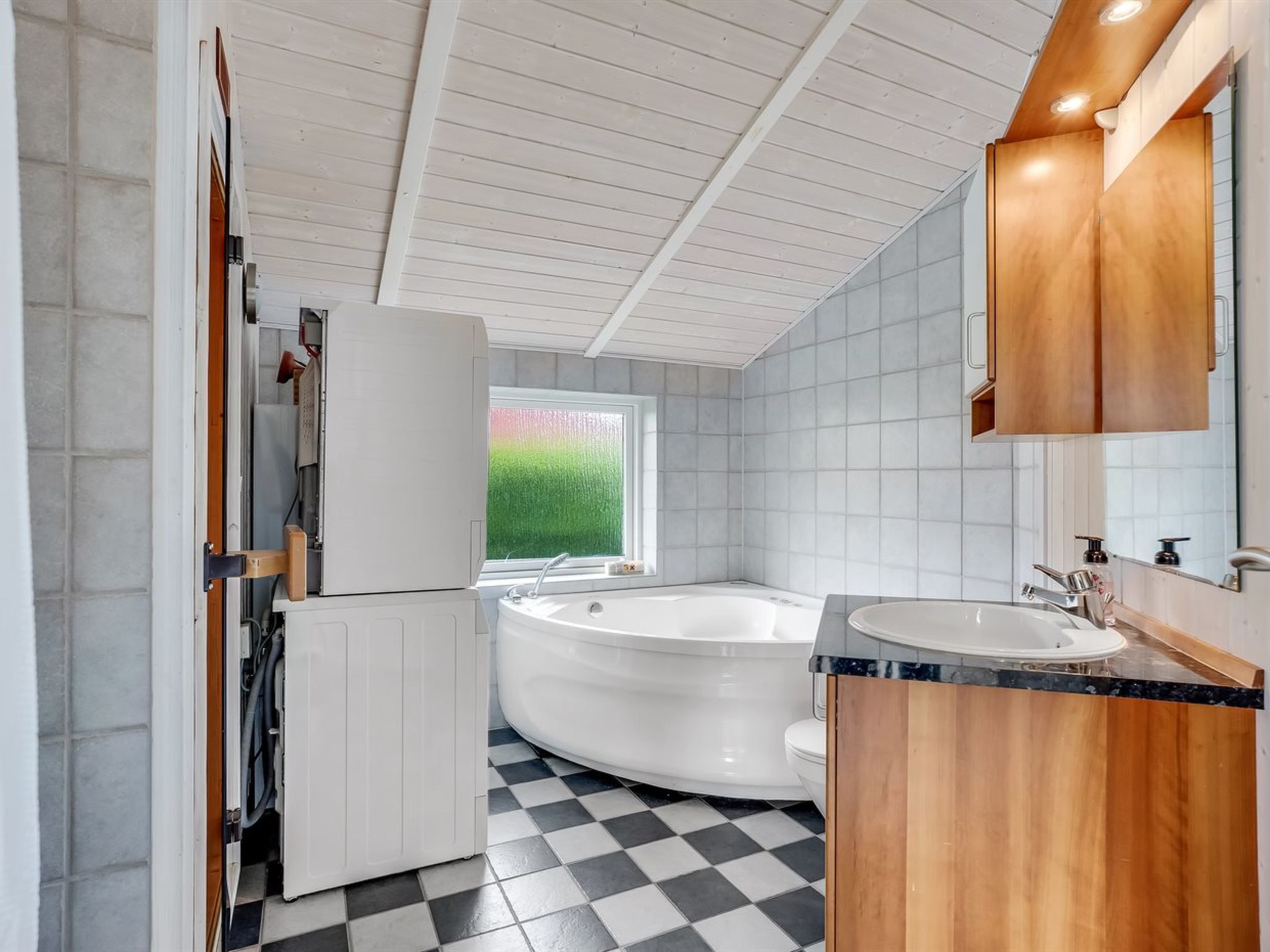 Une salle de bain moderne avec une baignoire sur pieds, un meuble-lavabo avec un miroir et une fenêtre donnant sur un paysage verdoyant.
