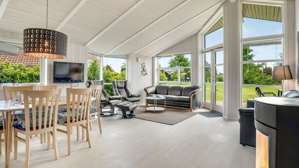 A spacious living area with a dining set, leather sofas, and a TV. - "Birtir" - 1.2km from the sea by Interhome (Væggerløse)