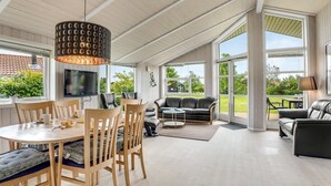 A spacious living area with a dining table, chairs, sofas, and a TV. - "Birtir" - 1.2km from the sea by Interhome (Væggerløse)