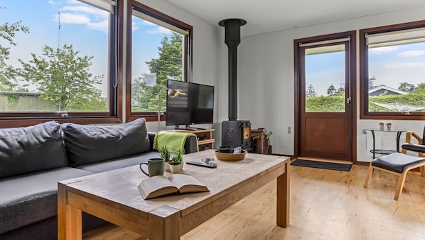 Un salon moderne avec un canapé, une table basse en bois, un téléviseur et un poêle à bois.