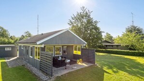 Une maison moderne de plain-pied dotée d’un patio couvert, d’un barbecue et d’une pelouse bien entretenue.