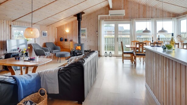 En mysig stuga med ett vardagsrum, en soffa, ett matbord och ett köksutrymme med en spis.