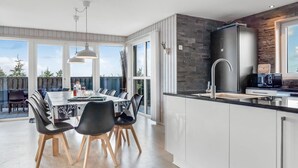 A modern kitchen with a large island, a dining area with a table and chairs, and a view of the outdoors.