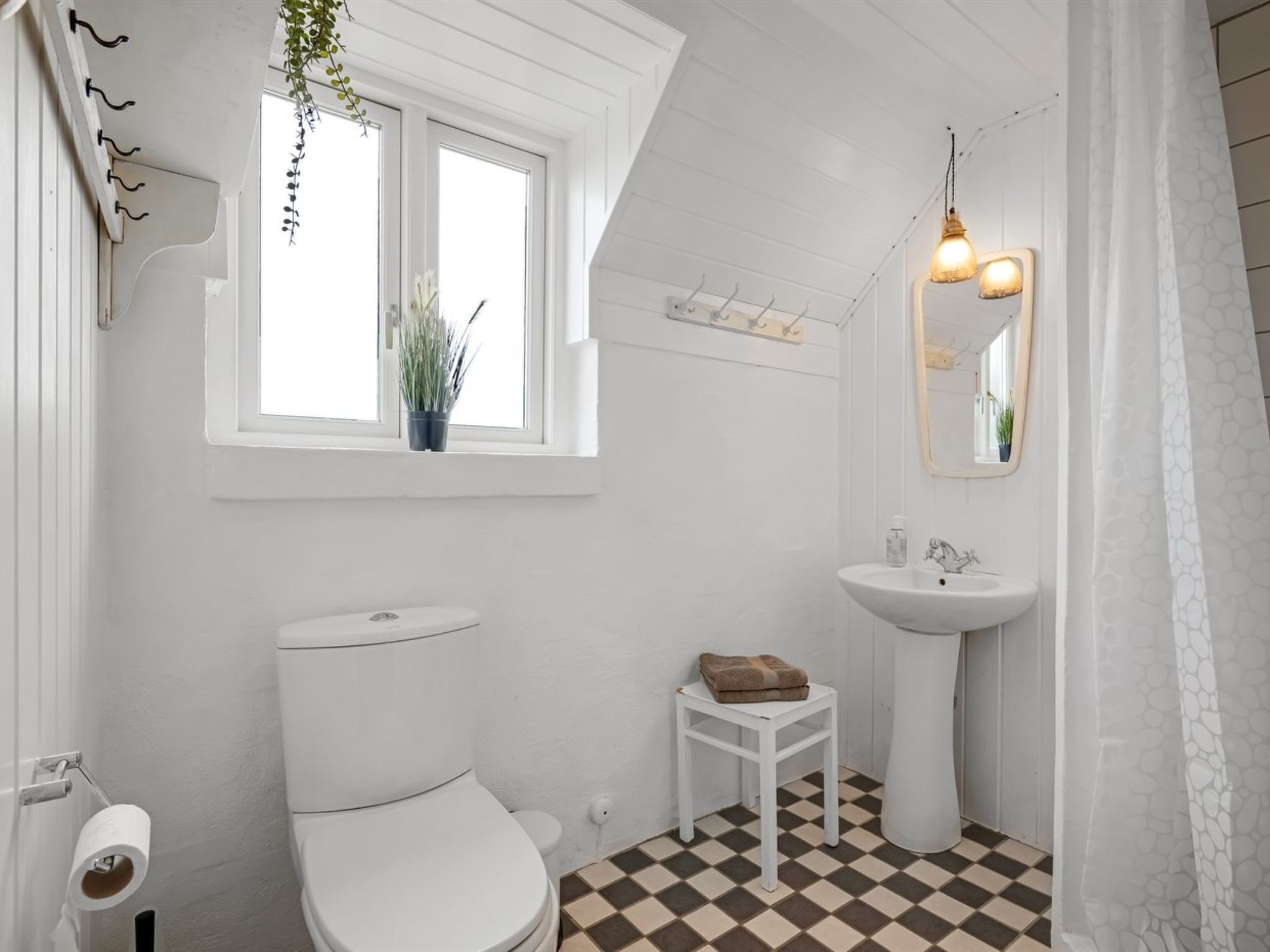 A bathroom with a toilet, sink, and window.