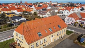 A large, yellow building with a red roof, multiple windows, and a small deck area. - "Gerrit" - 450m from the sea by Interhome (Løkken)