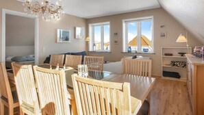 A cozy, well-lit dining area with wooden furniture, a chandelier, and large windows offering a view of the outside. - "Gerrit" - 450m from the sea by Interhome (Løkken)