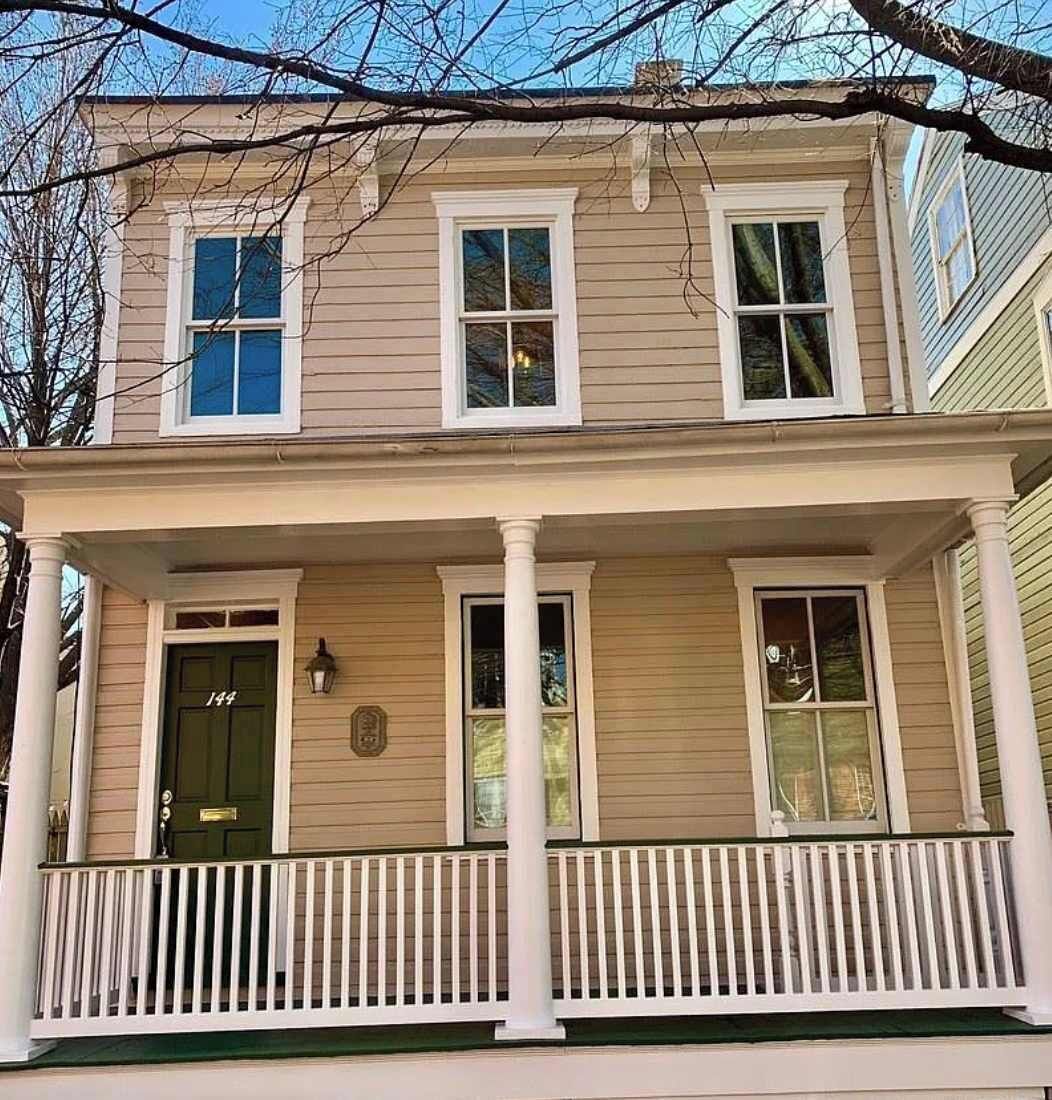 A two-story house with a front porch, a green door, and a mailbox.