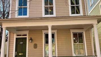 A two-story house with a front porch, a green door, and a mailbox.
