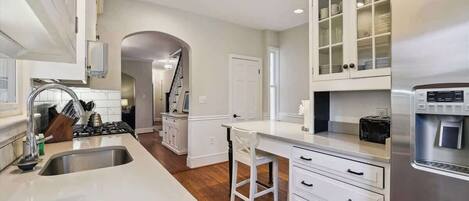 A modern kitchen with white cabinetry, a stainless steel refrigerator, and a built-in coffee machine.