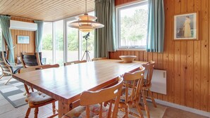 Een kamer met houten lambrisering, een grote eettafel, stoelen en een lamp op een statief.