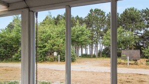 Een overdekt terras met uitzicht op een zandweg en bomen.