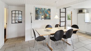 Een eethoek met een tafel, stoelen, een schilderij en een ladder.
