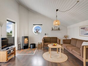 A modern living room with a fireplace, a television, a sofa, and a round table with fruit.