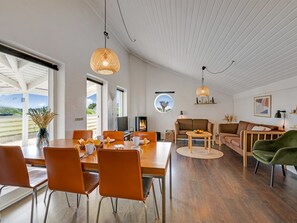 Un vaste espace de vie comprenant une table à manger, des canapés et une cheminée.