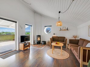 A modern living room with a television, sofas, a fireplace, and a view through a glass door.