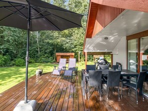 An outdoor deck with wooden flooring, a grill, and seating.