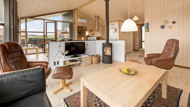 Un amplio salón con una televisión grande, una chimenea, sillones de cuero y una mesa de comedor con fruta.