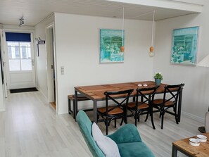 A dining area with a wooden table and chairs, a teal sofa, and two wall-mounted light fixtures. - "Ingeborre" - 100m to the fjord by Interhome (Vestervig)