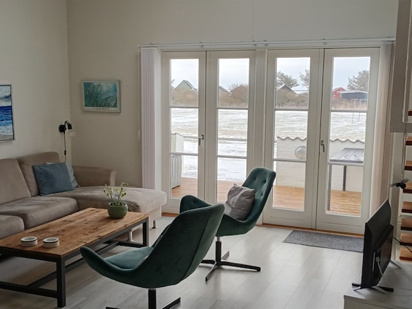 Una sala de estar con un sofá, dos sillones, una mesa de madera y un televisor.