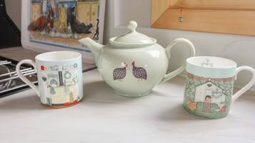 A kitchen setting with a white teapot and two mugs with animal illustrations.
