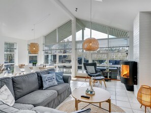 Ett modernt vardagsrum med en grå soffa, ett runt soffbord och en öppen spis.