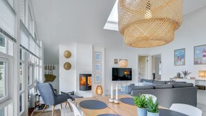 Una sala moderna con una mesa de comedor de madera, sofás grises y un televisor grande.