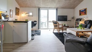 Eine moderne Wohnung mit Küchenzeile, Essbereich, Wohnzimmer mit Sofa und Fernseher sowie ein Balkon mit Blick.