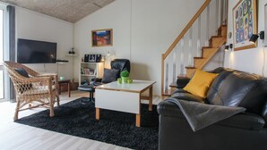 Ein modernes Wohnzimmer mit einer Couch, einem Couchtisch, einem Bücherregal, einem Fernseher und einer Treppe.