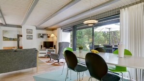 Een moderne woonkamer met een bank, televisie en een eethoek met stoelen en een tafel.