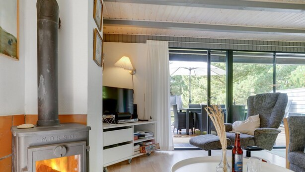 Een knusse woonkamer met een houtkachel, een flatscreen televisie en een eethoek met buitenmeubilair.