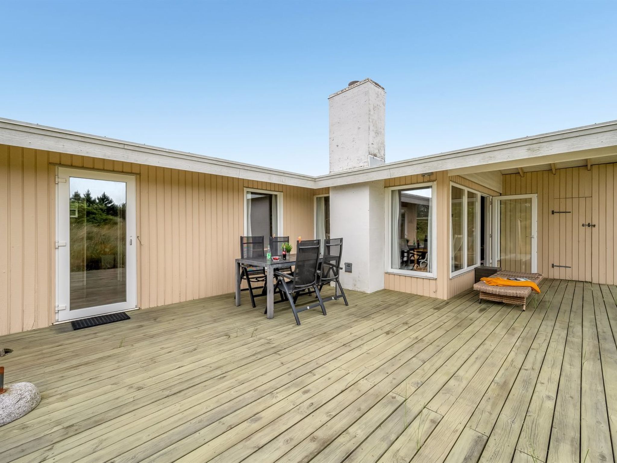 Una terraza de madera con comedor y zona de estar.