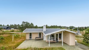 Een modern huis met een overdekt terras, een groot raam en een schotelantenne.