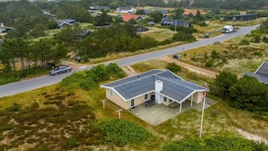 A modern house with a sloped roof, surrounded by a grassy area and a road.