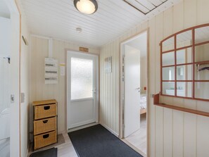 A hallway with a door leading to a bedroom, a small storage unit, and a wall-mounted air conditioning unit.
