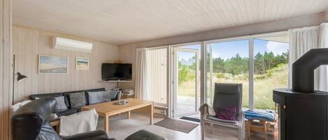 Ein modernes Wohnzimmer mit einer Couch, einem Couchtisch, einem Fernseher und einem Kamin.