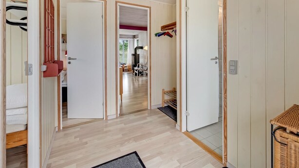 A hallway with wooden flooring, white doors, and a ceiling light fixture.