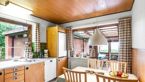 Cocina compacta con muebles de madera, un lavamanos y un comedor con mesa y sillas.