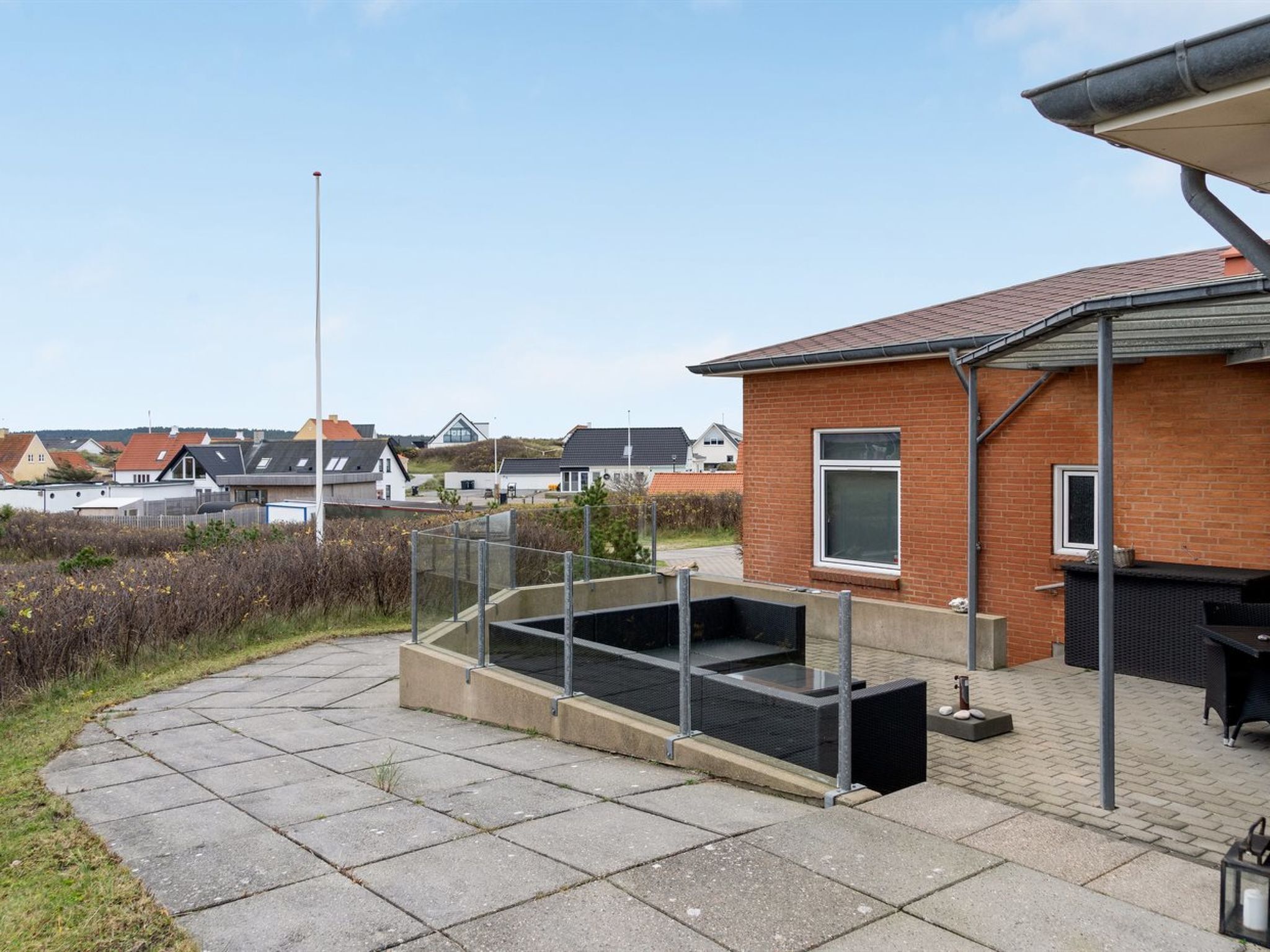 A residential area with a brick house, a concrete patio, and a metal fence.