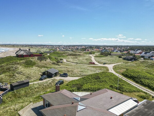 A coastal village with houses, a beach, and a dirt road.