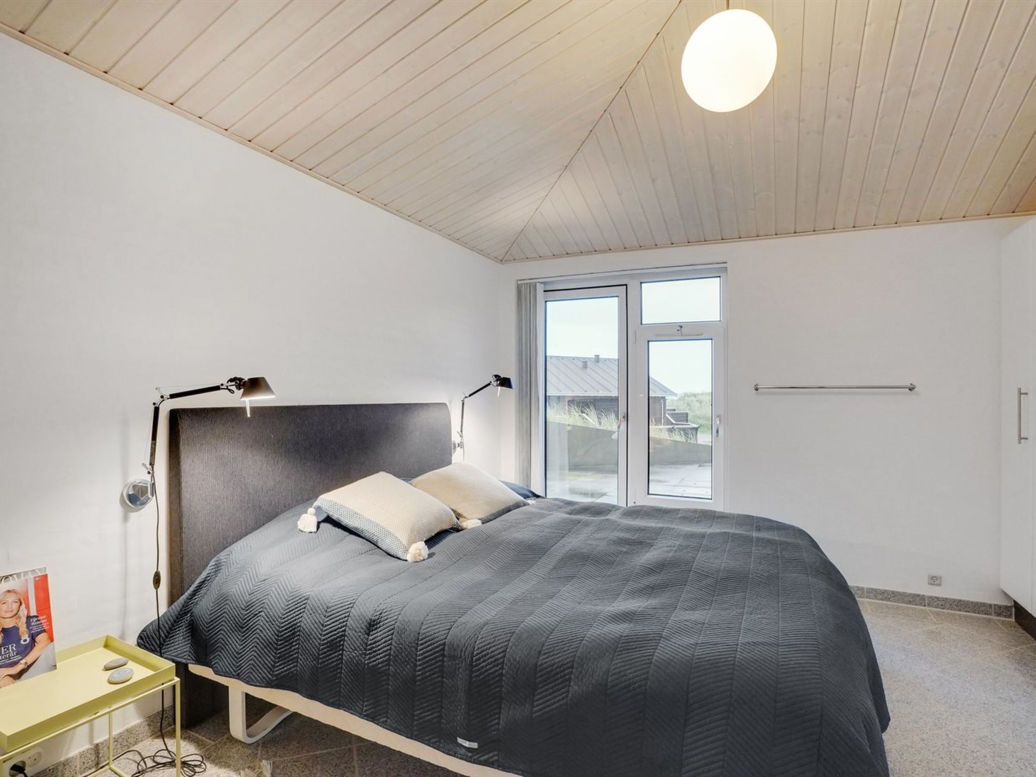 Un dormitorio con una cama, lámparas de noche, una mesita de noche y una ventana con vistas.
