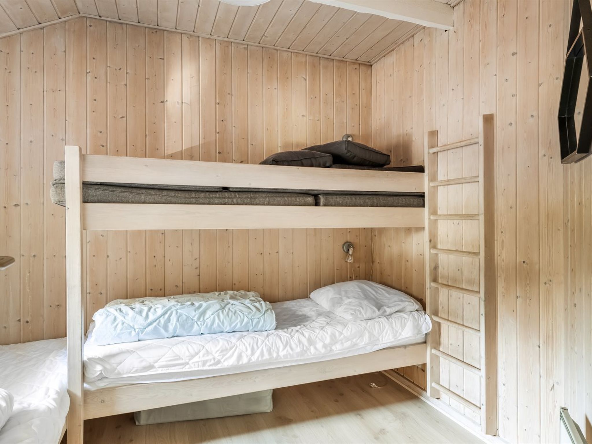 Une chambre avec un lit superposé, des murs en bois et une échelle.