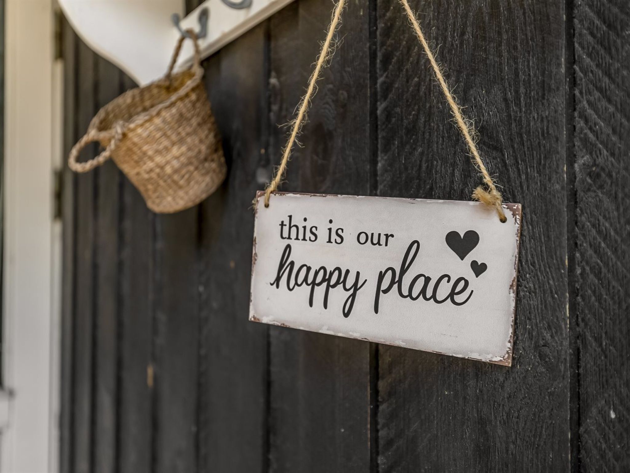 Une pancarte rustique portant l’inscription « ici, nous sommes heureux » est accrochée à un mur en bois.