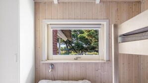 A single bed with a white mattress and a window above it.