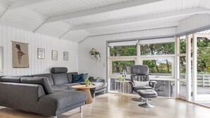 A modern living room with a grey sectional sofa, a small round table, and a leather chair.