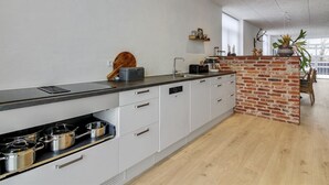 Eine moderne Küche mit weißen Schränken, einer schwarzen Arbeitsplatte und einer Ziegelwand.