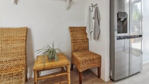 Eine moderne Küche mit Korbmöbeln, einem Edelstahl-Kühlschrank und einem kleinen Holztisch mit Pflanze.