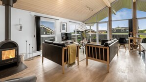 A spacious living room with a fireplace, large windows, and a high ceiling. - "Samuil" - 300m to the fjord by Interhome (Vinderup)